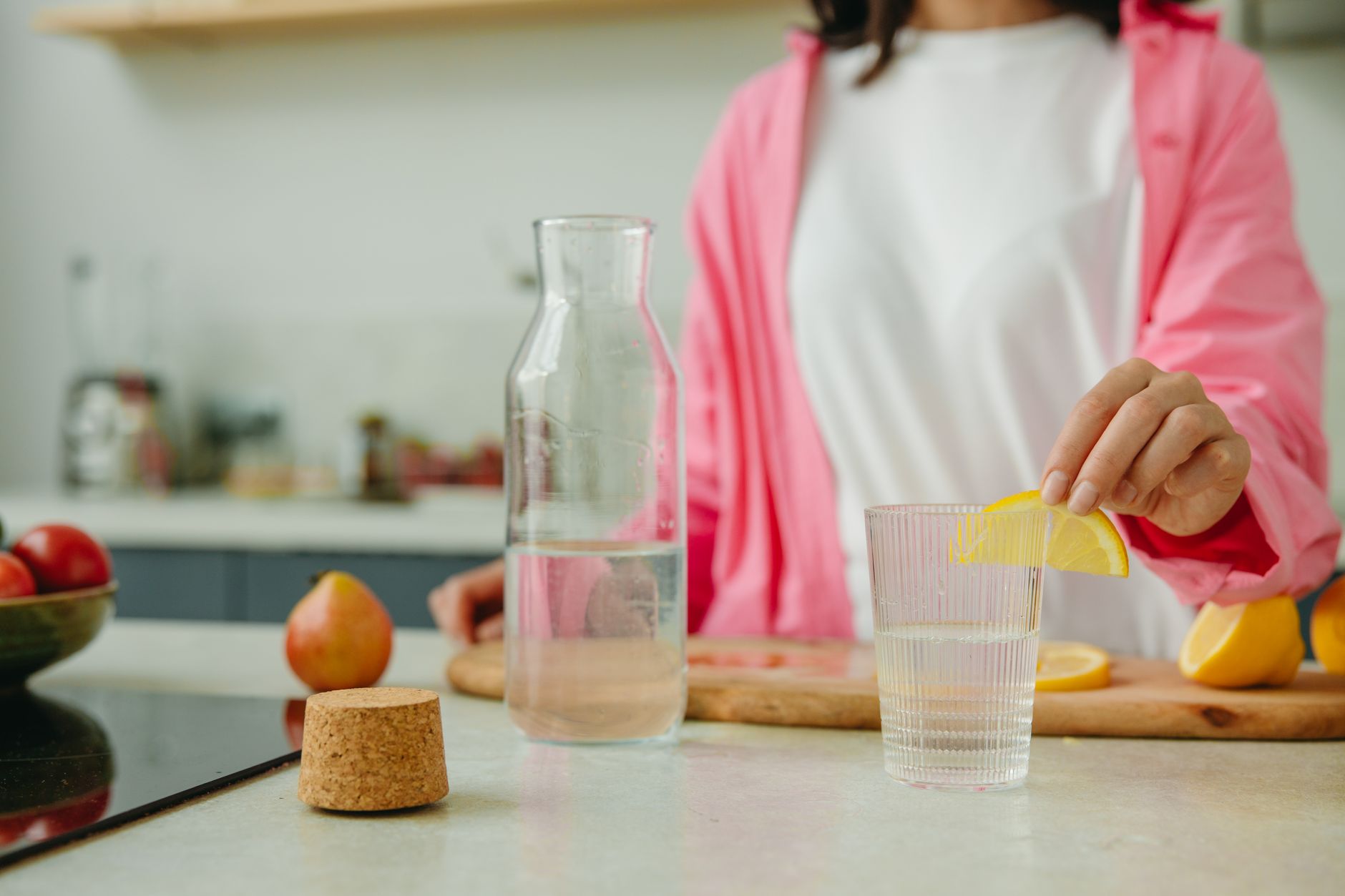 woman putting sliced lemon on a glass of water